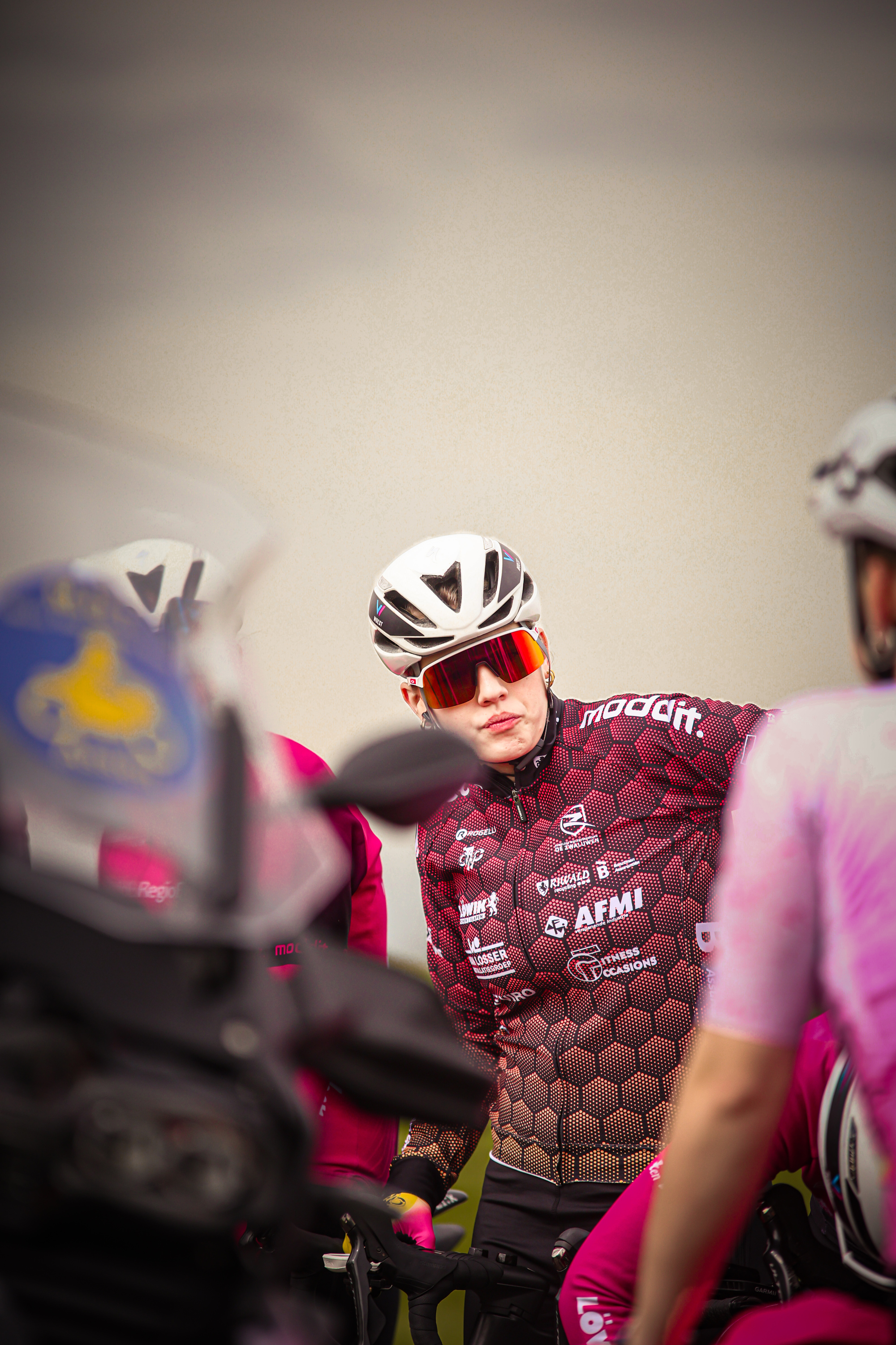 A man in a pink and black shirt is riding a motorcycle on the track of a race.