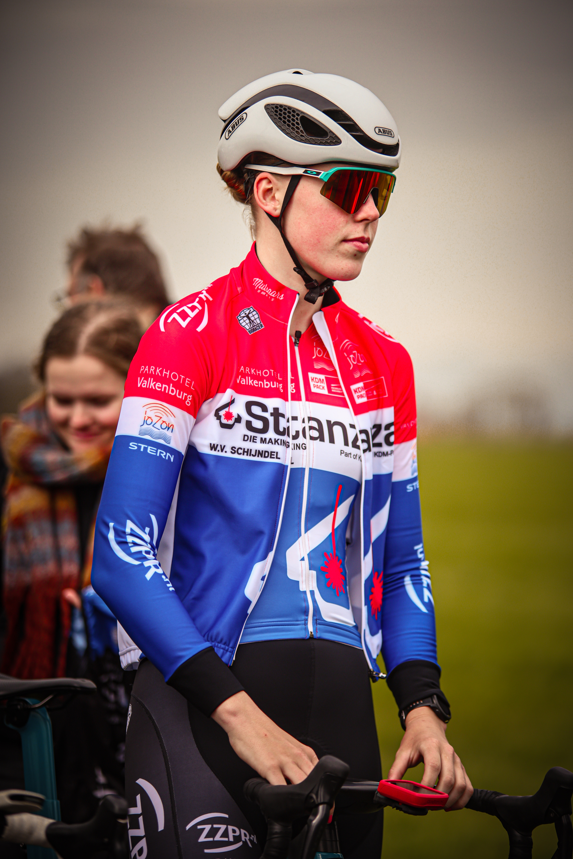 A person wearing a red and blue cycling jersey is riding their bike.