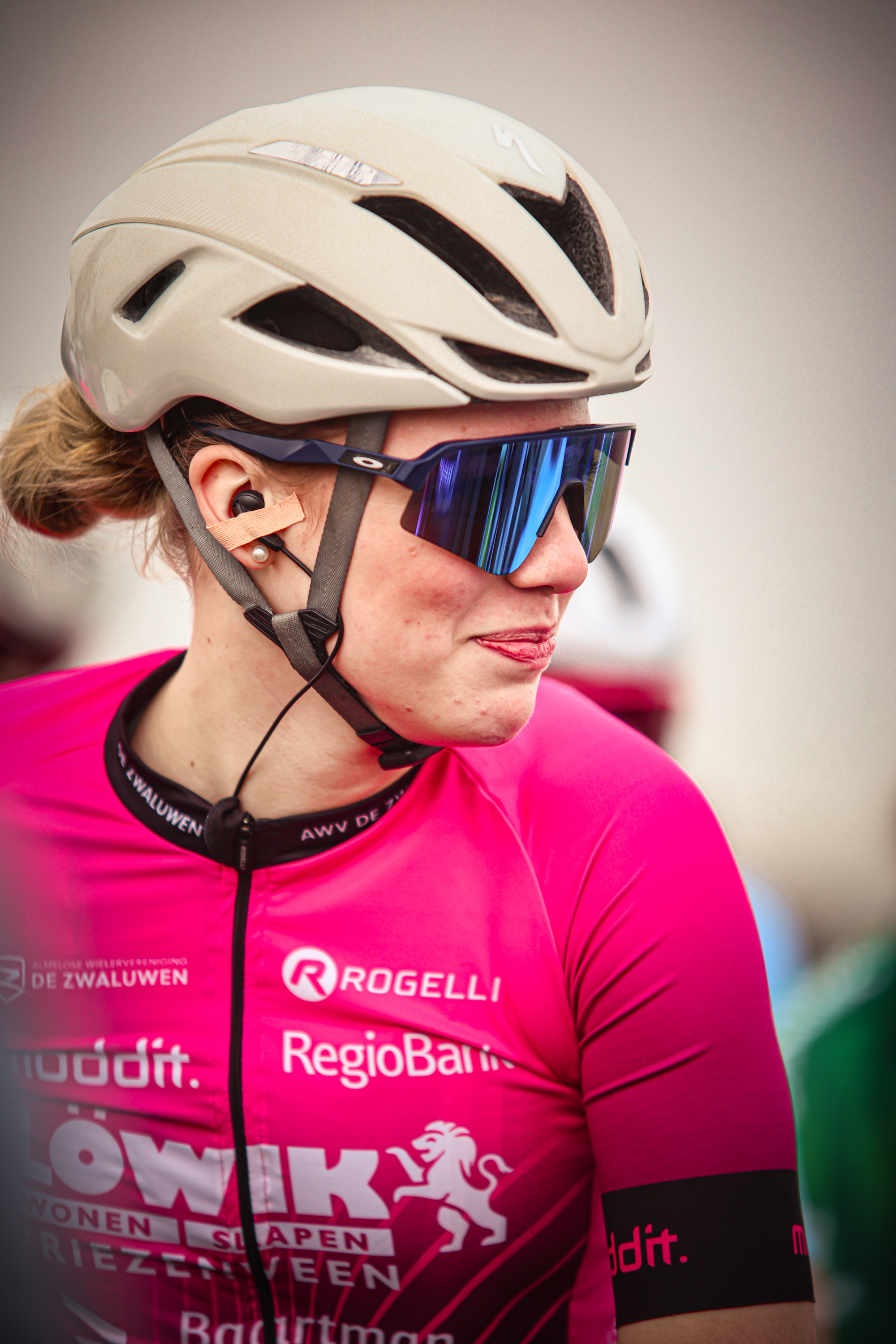 A woman in a pink shirt and bike helmet is wearing sunglasses.