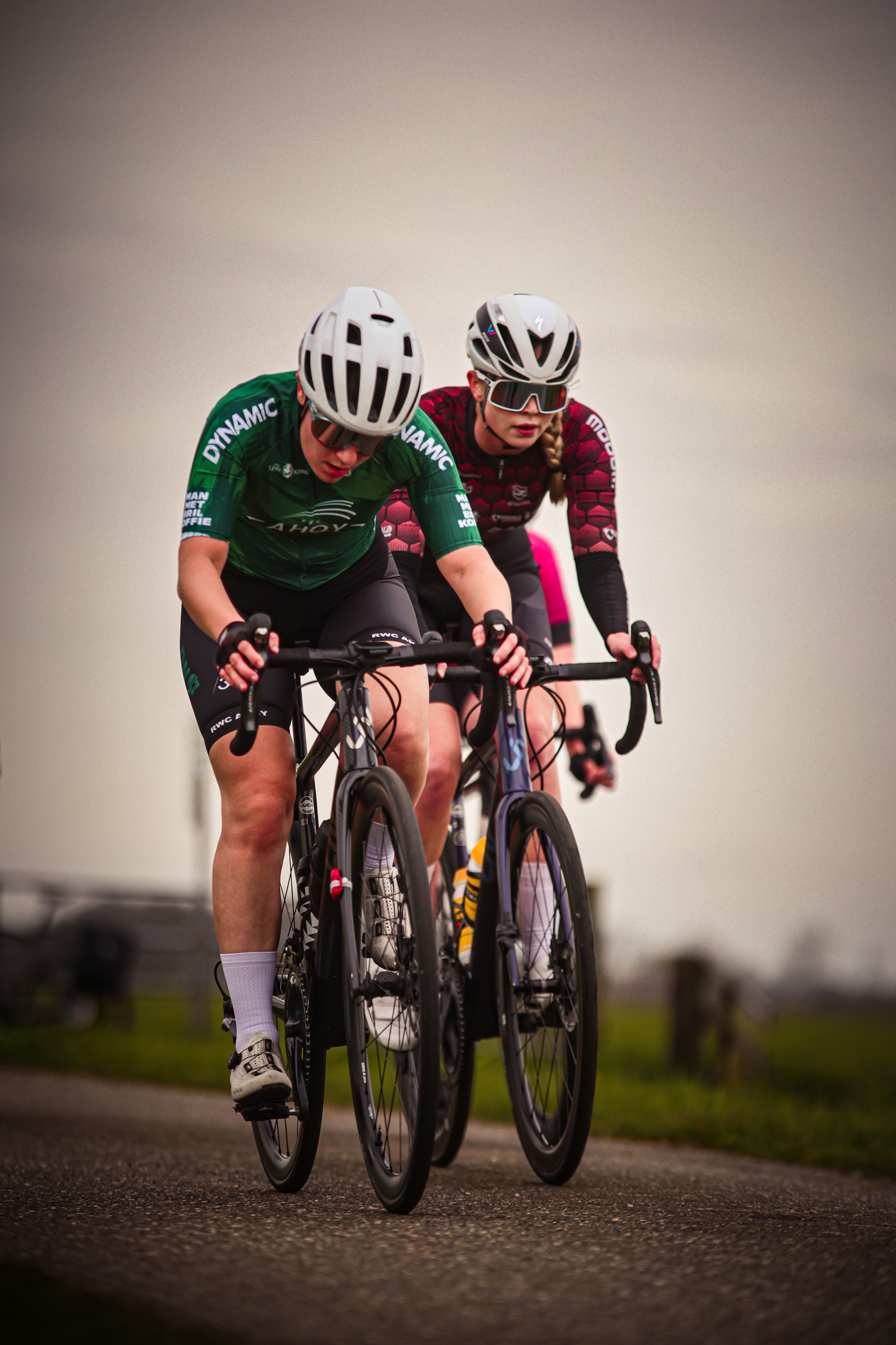 Two people riding bikes, one is wearing a green and black jersey with the number 4 on it.