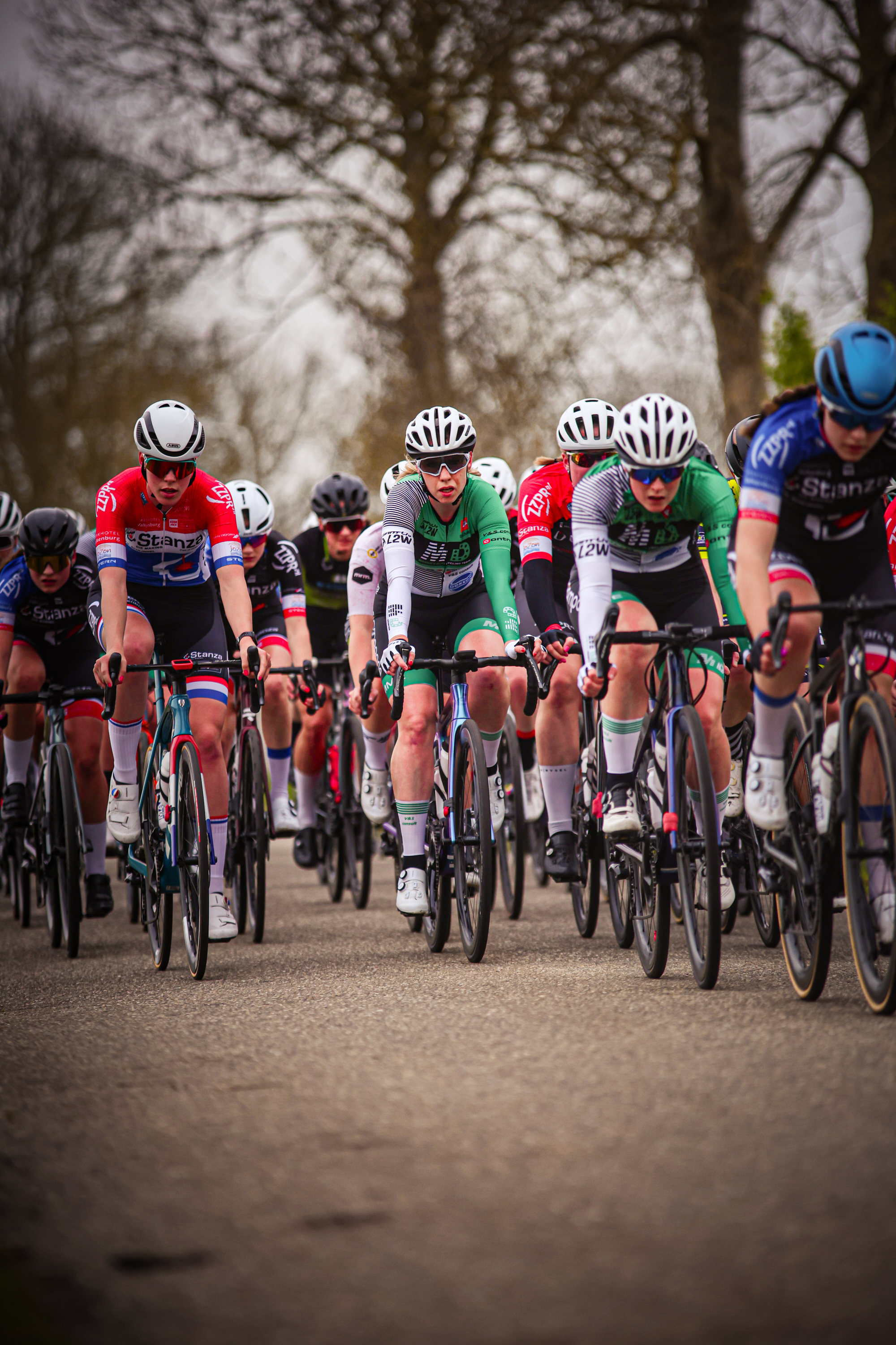 The cyclists are in the middle of a race and they're all wearing helmets to protect their heads.