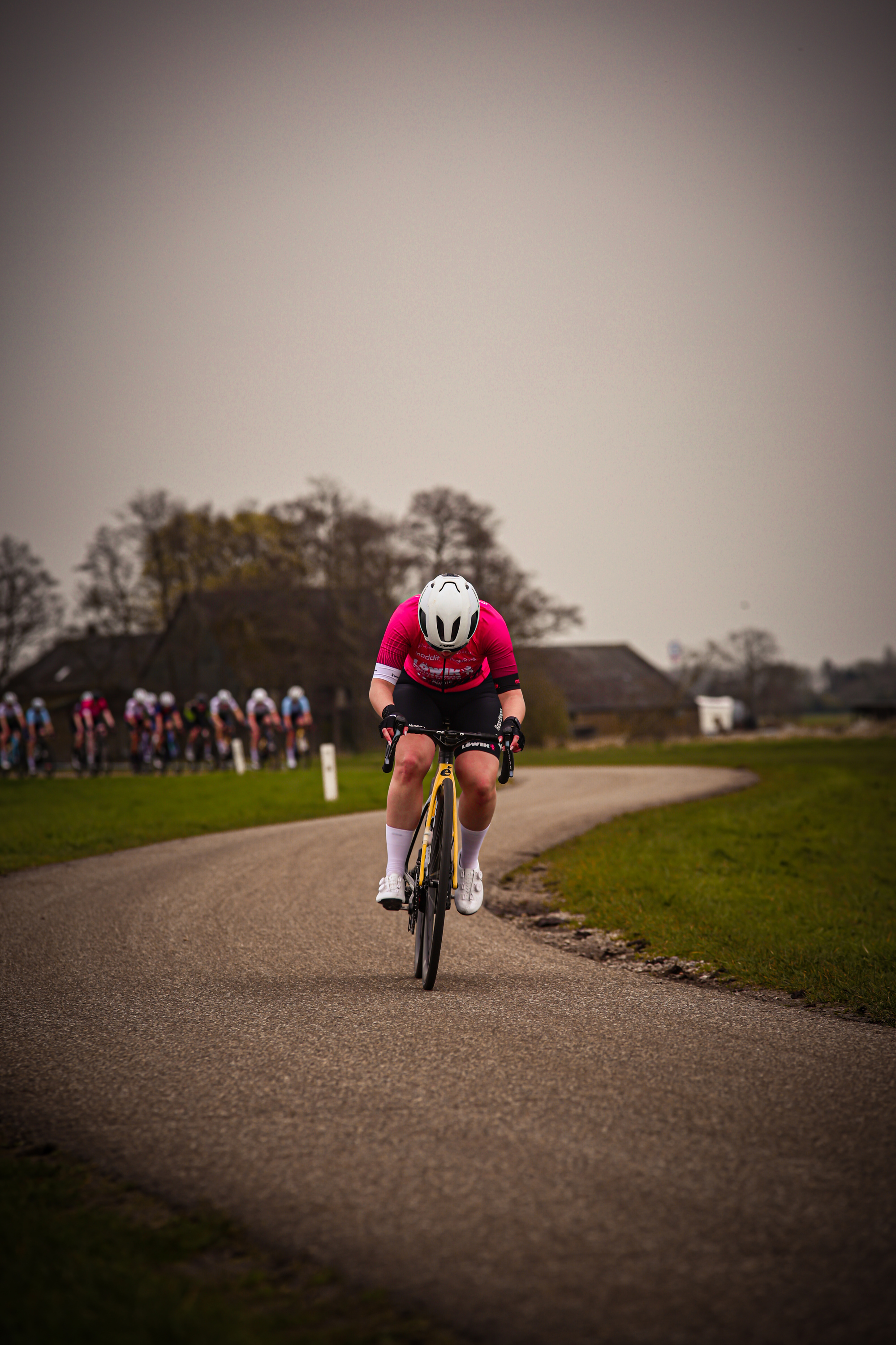 A cyclist is riding down a road, wearing a helmet and white shoes.