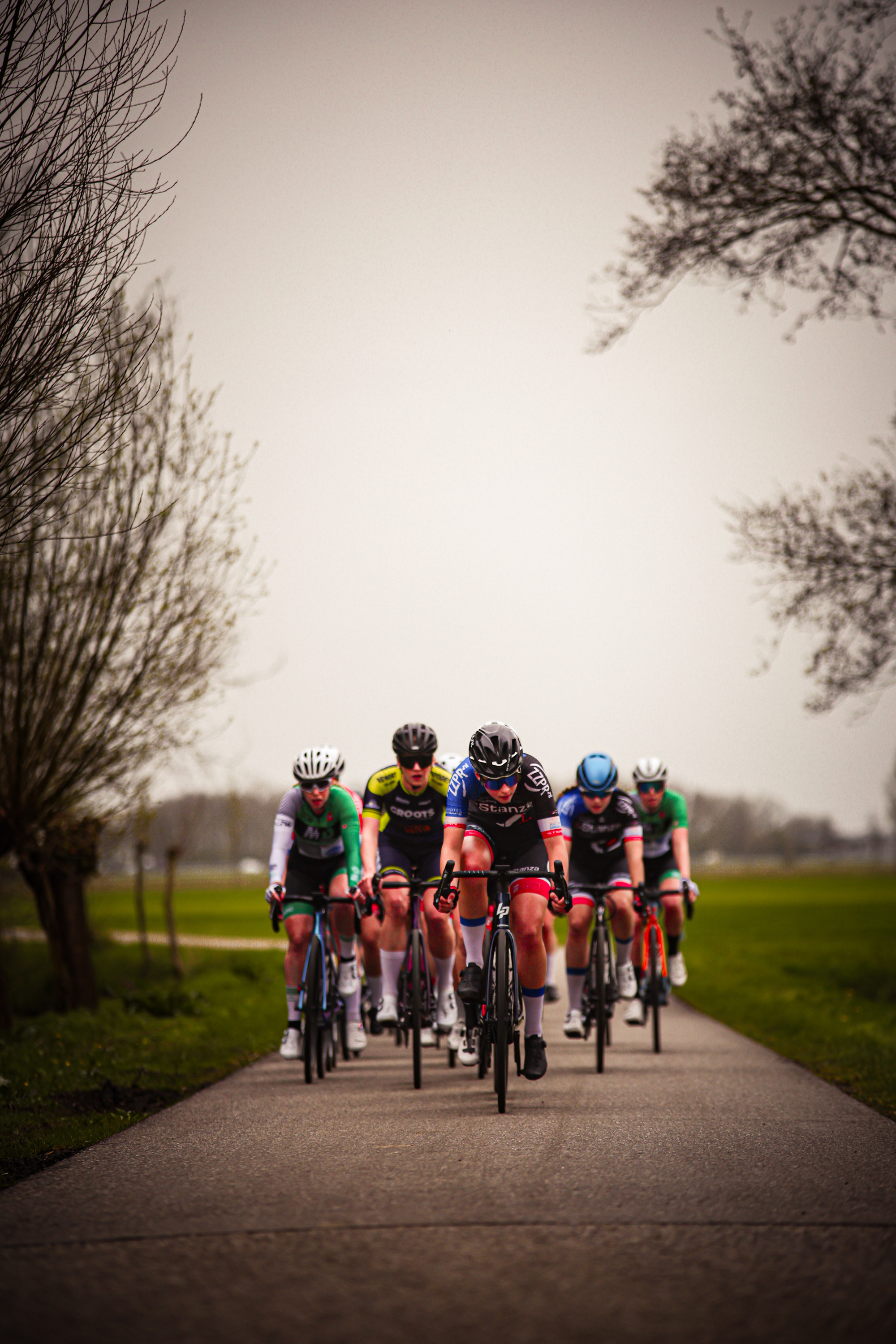 A group of bicyclists on a road, with one wearing a blue helmet.