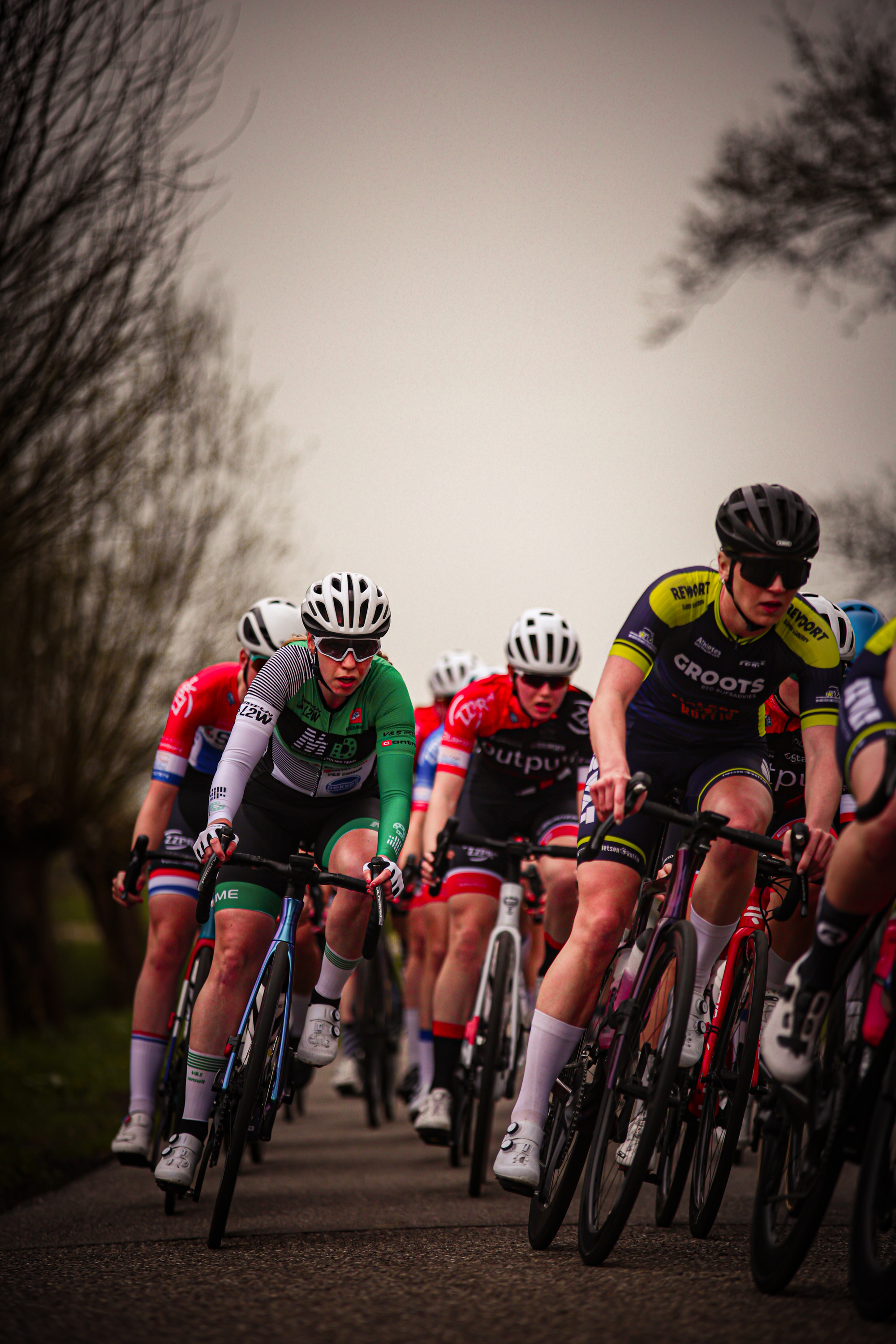 A group of cyclists, one wearing a white jersey with the number 4 and another in a black jersey with the number 2.