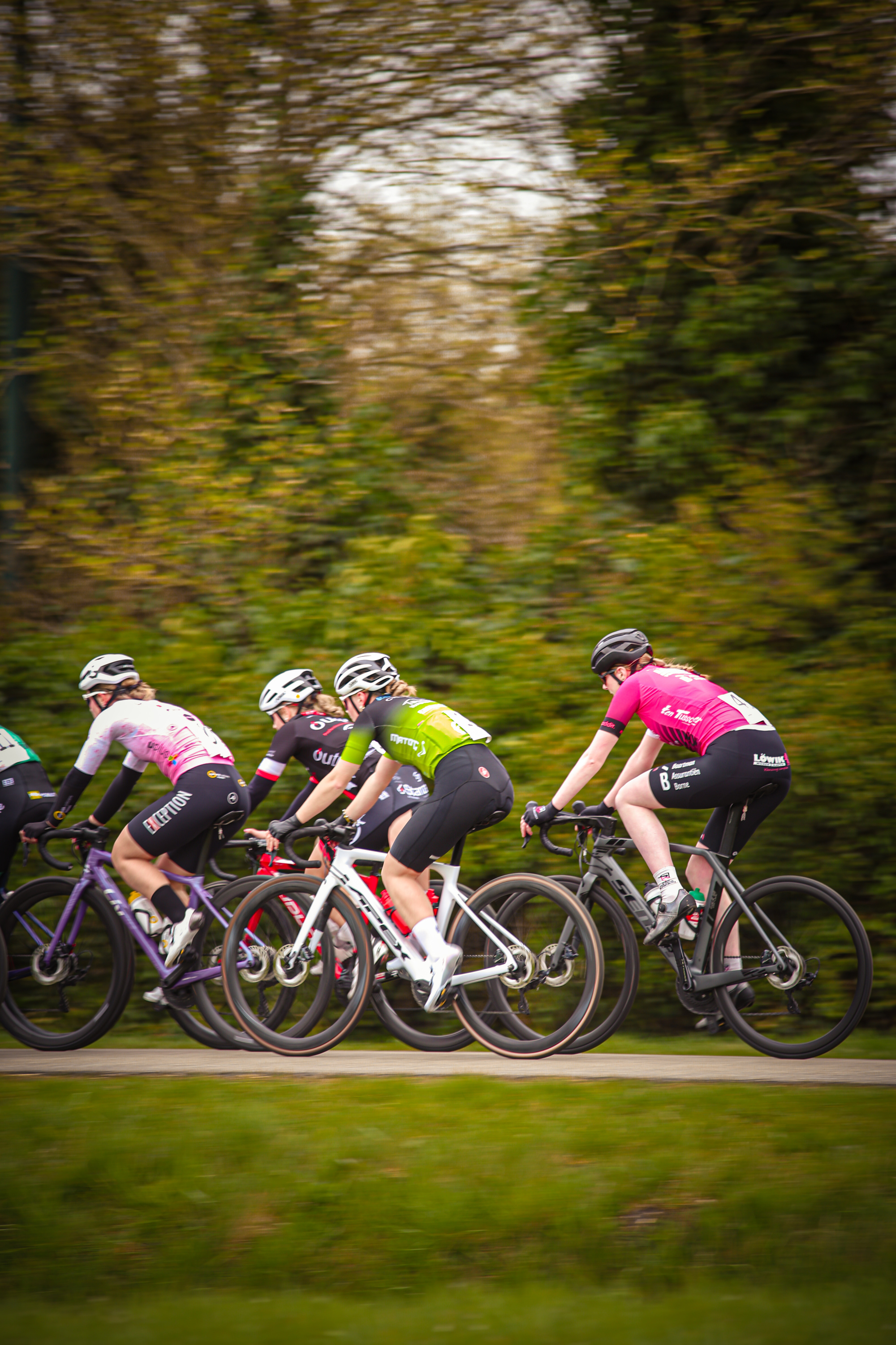 Several cyclists wearing protective gear are riding on a grassy area. They appear to be participating in a cycling event.