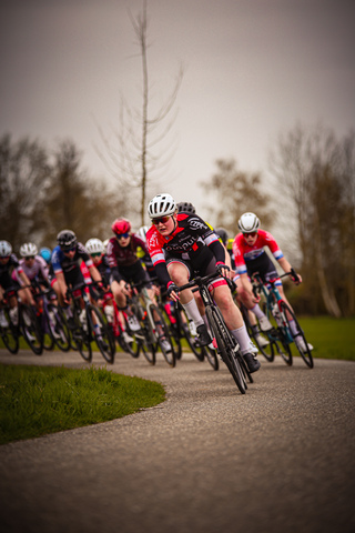 A group of cyclists race along a winding path at night.