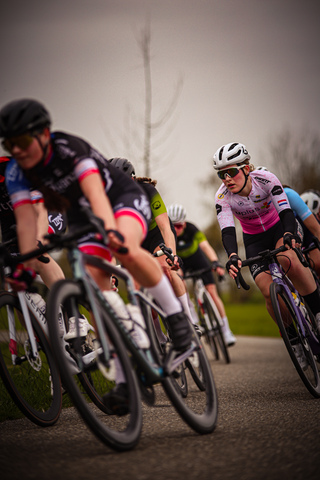 Three women on bikes in a race sponsored by Ronde Van De Lichtmis.