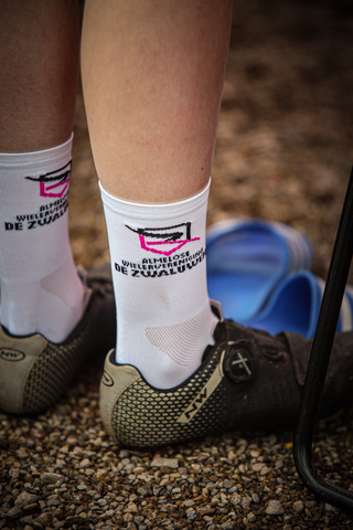 A person is wearing a white sock that says "Wielrennen, Ronde van de Lichtmis" on it.