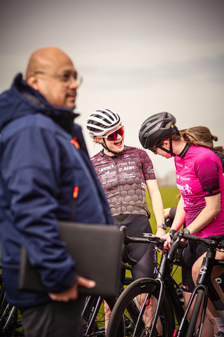 Three women wearing bike helmets standing next to each other.