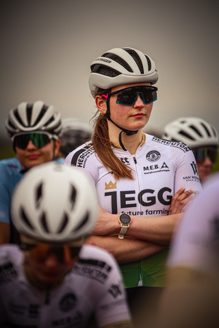 A woman is wearing a white and green jersey with the word "TEGGER" written on it. She's also holding a watch in her hand.