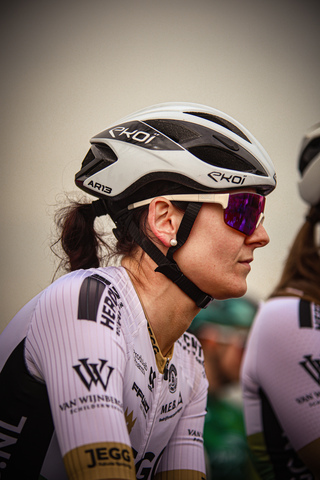 A woman in a cycling uniform is wearing a white and black bike helmet.