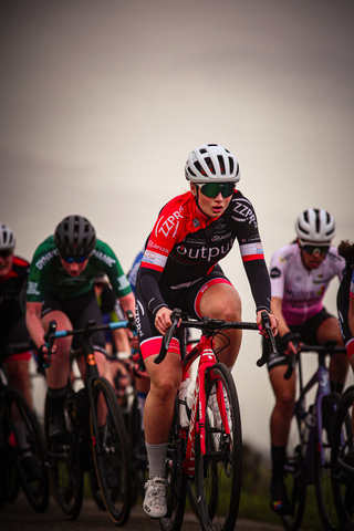 A group of cyclists on a race track sponsored by Wielrennen.