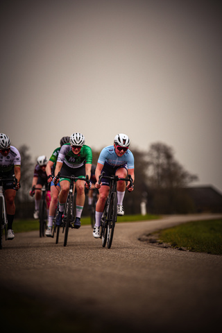 Racers on a road, with one wearing green and blue.