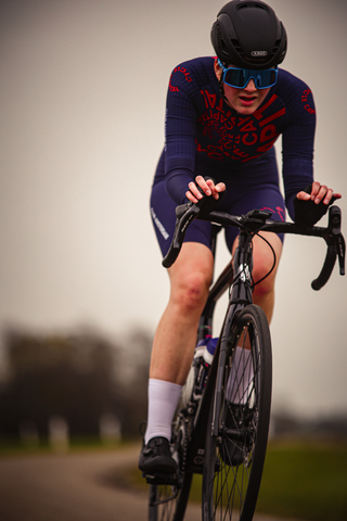 A person wearing a blue and red outfit is riding a bike.