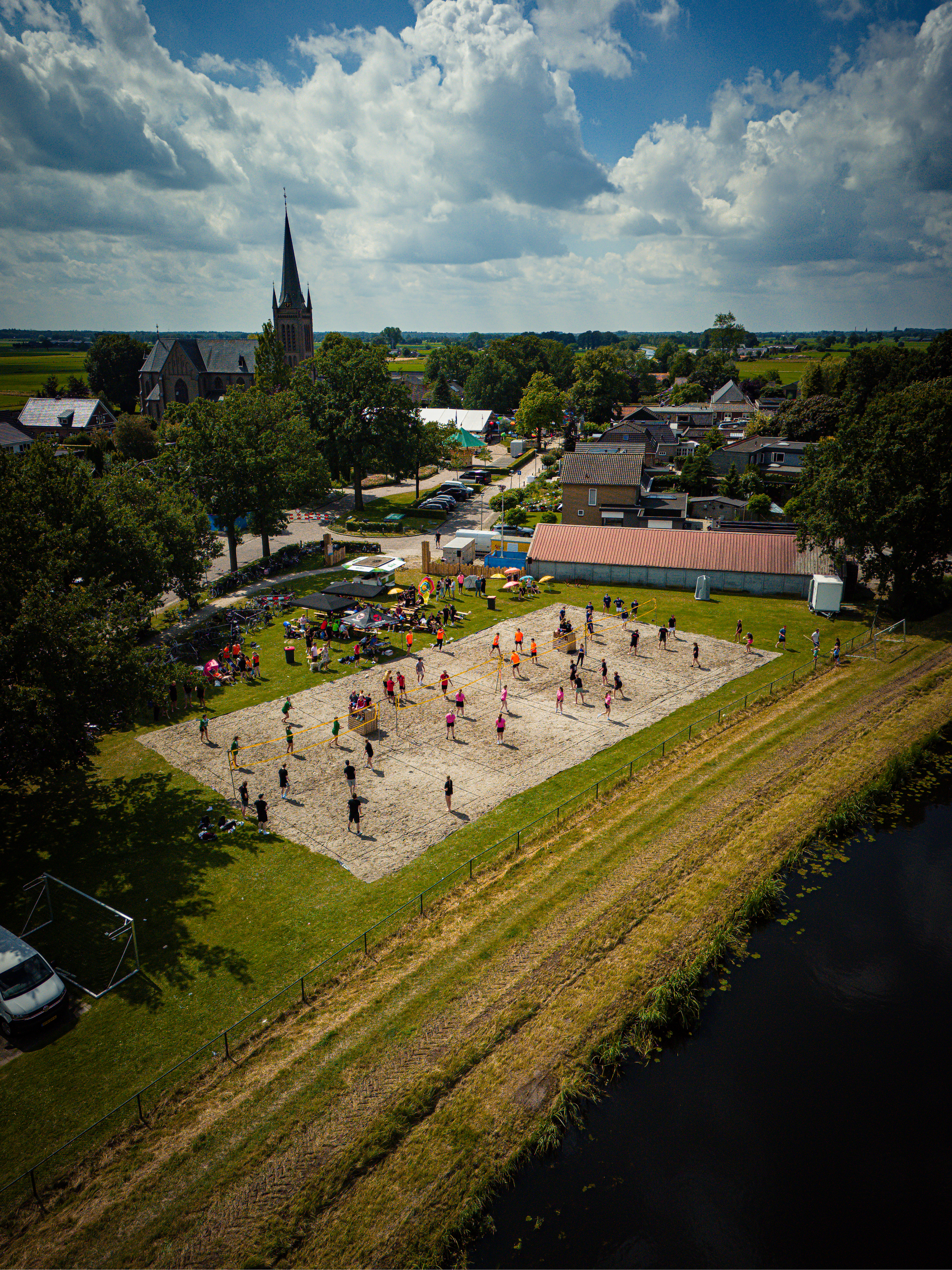 a beach volleyball game in progress, people playing with a big tent.