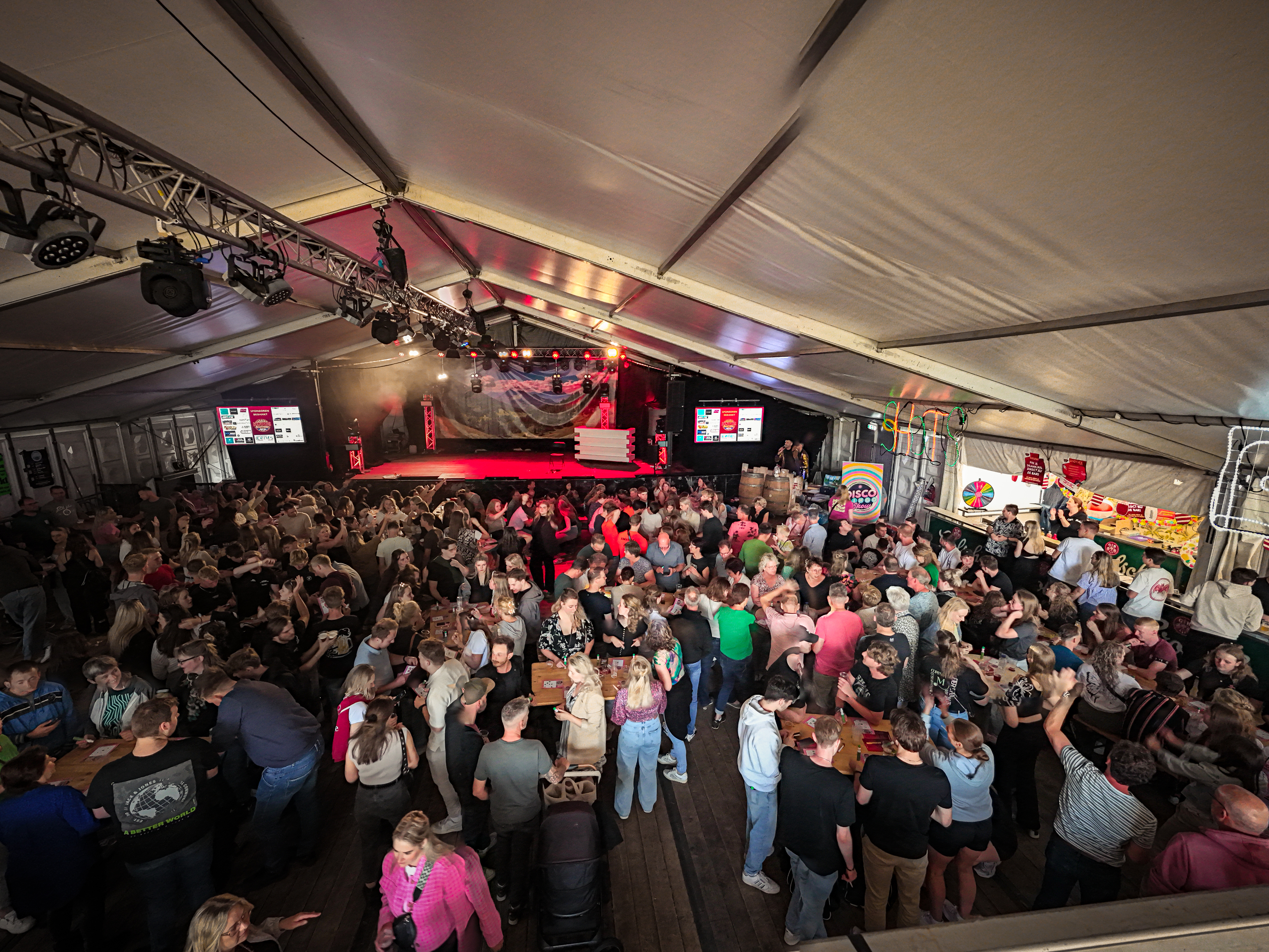 A large group of people gathered in a tent at an event sponsored by Beach Volleybal.