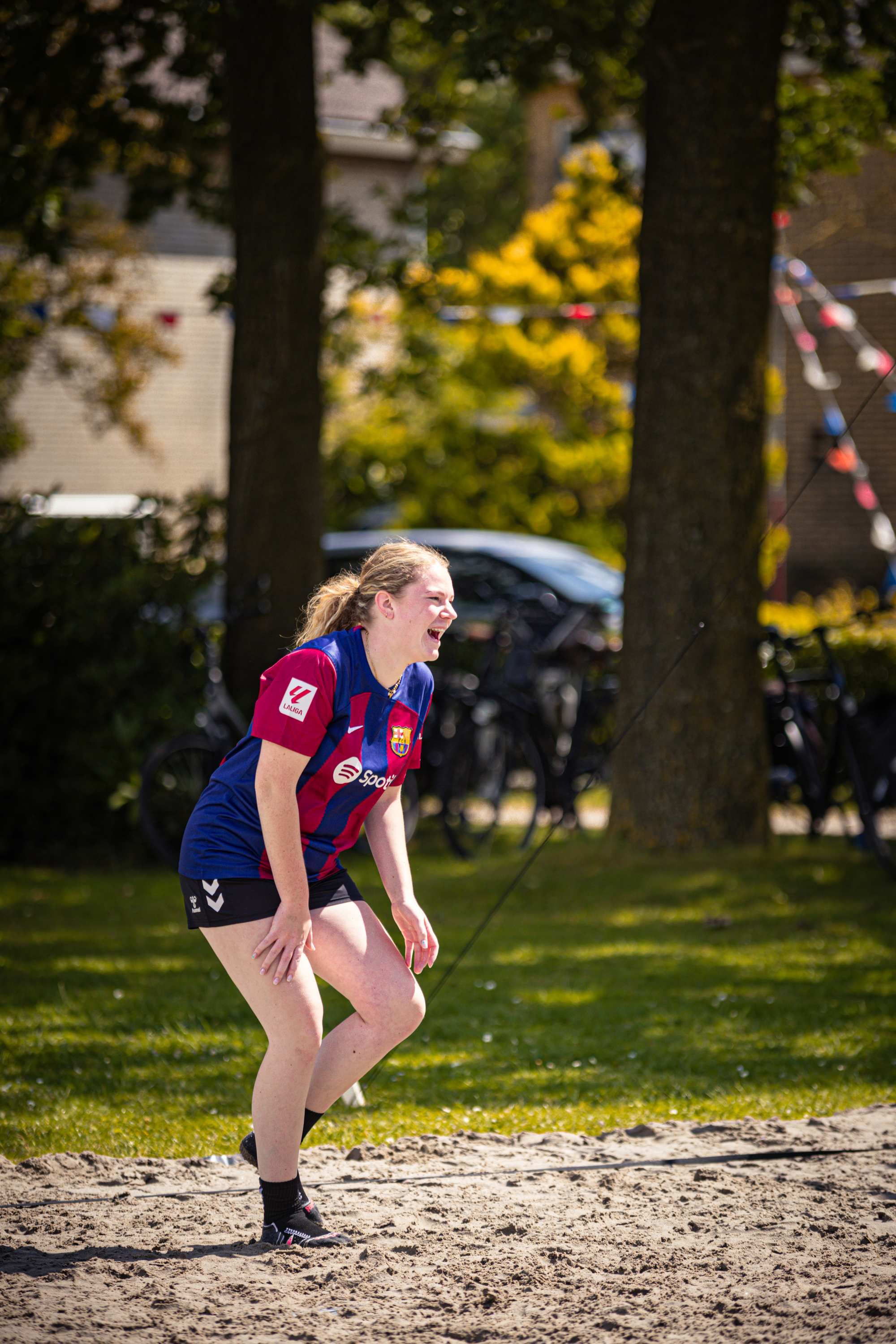 a lady in a blue and red beach outfit playing volleyball on the sand.