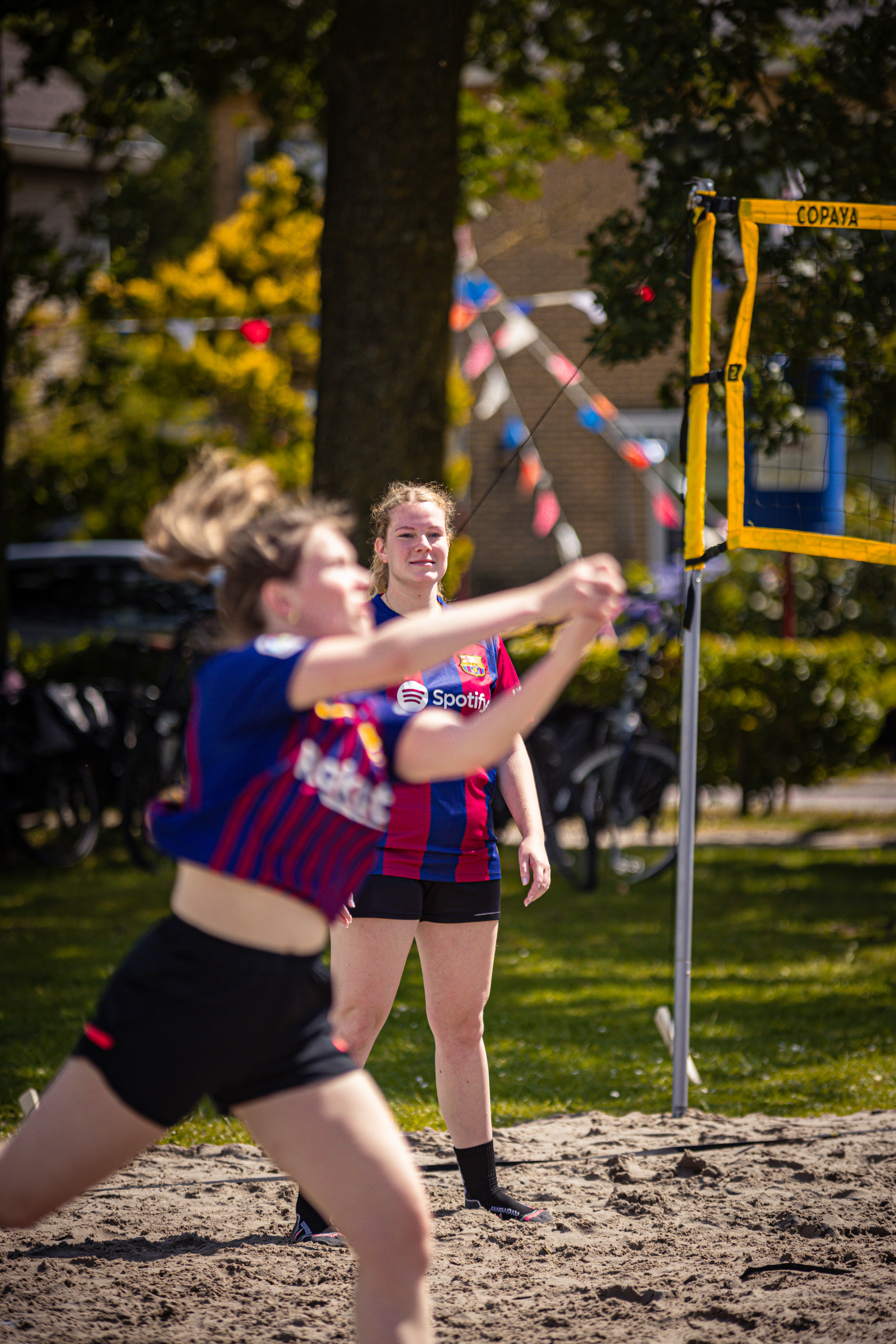 A young girl in a red and blue jersey is about to hit the ball.