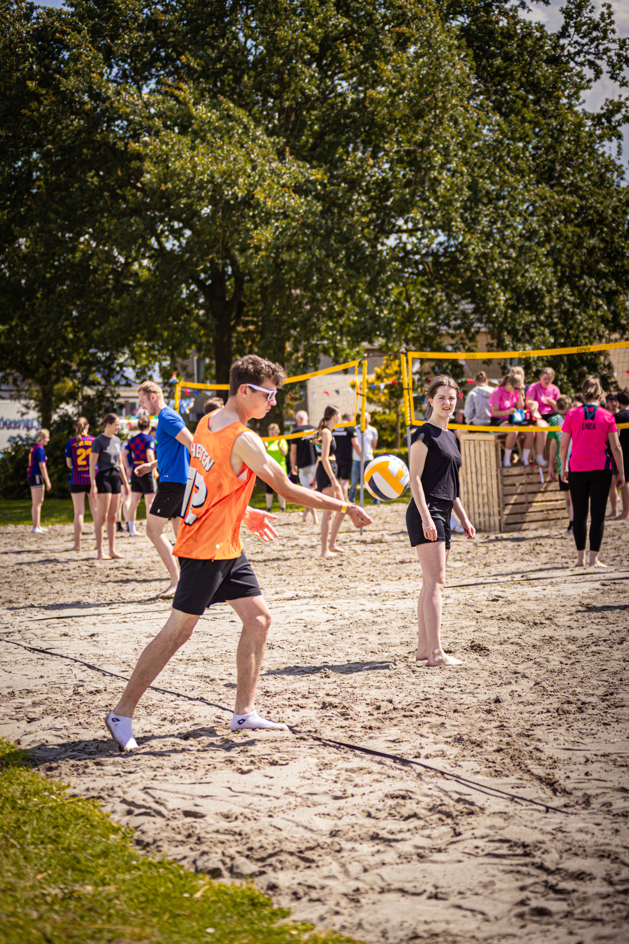 A group of people on a sandy beach are enjoying a game of volleyball.