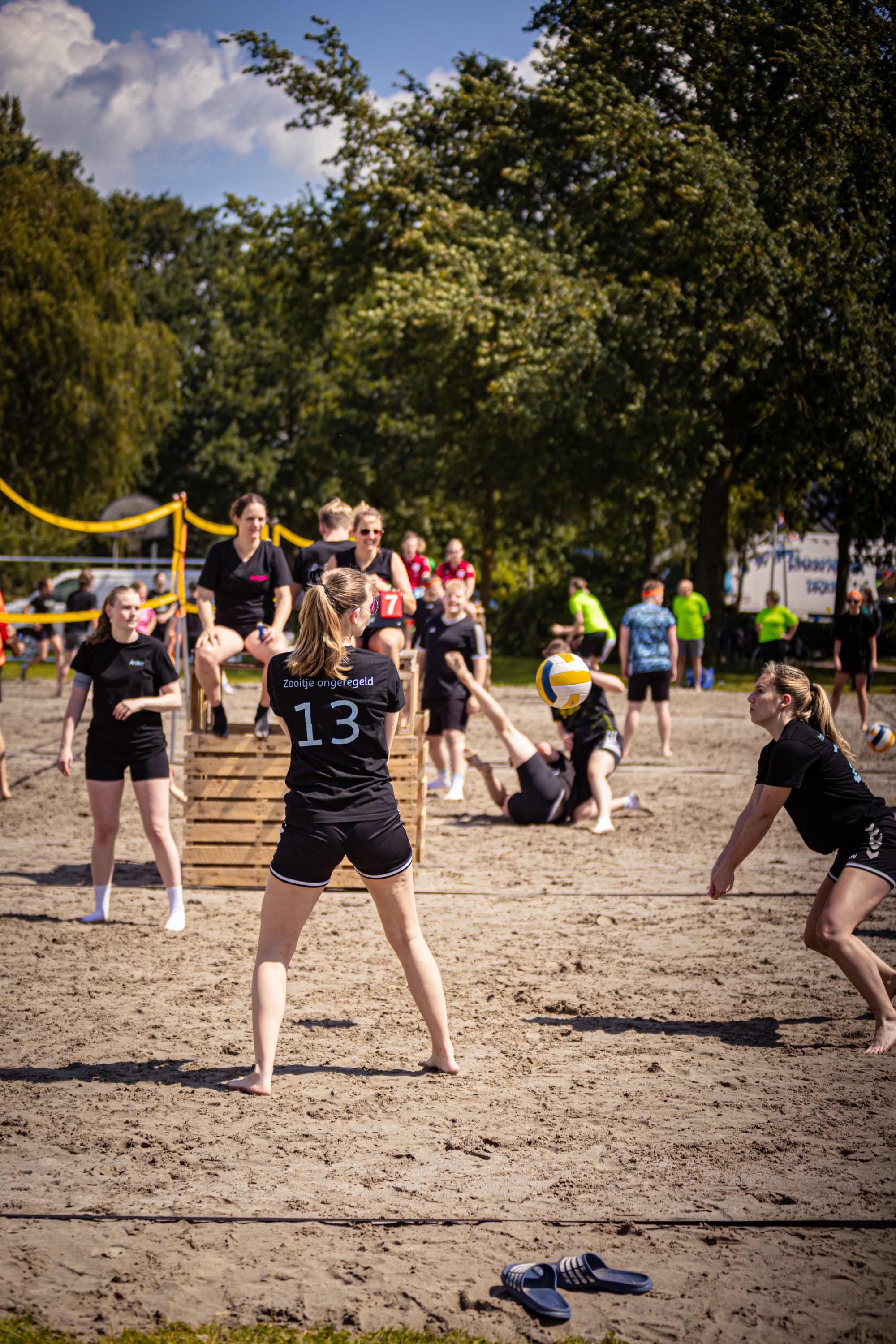 A group of people play beach volleyball on a sunny day.