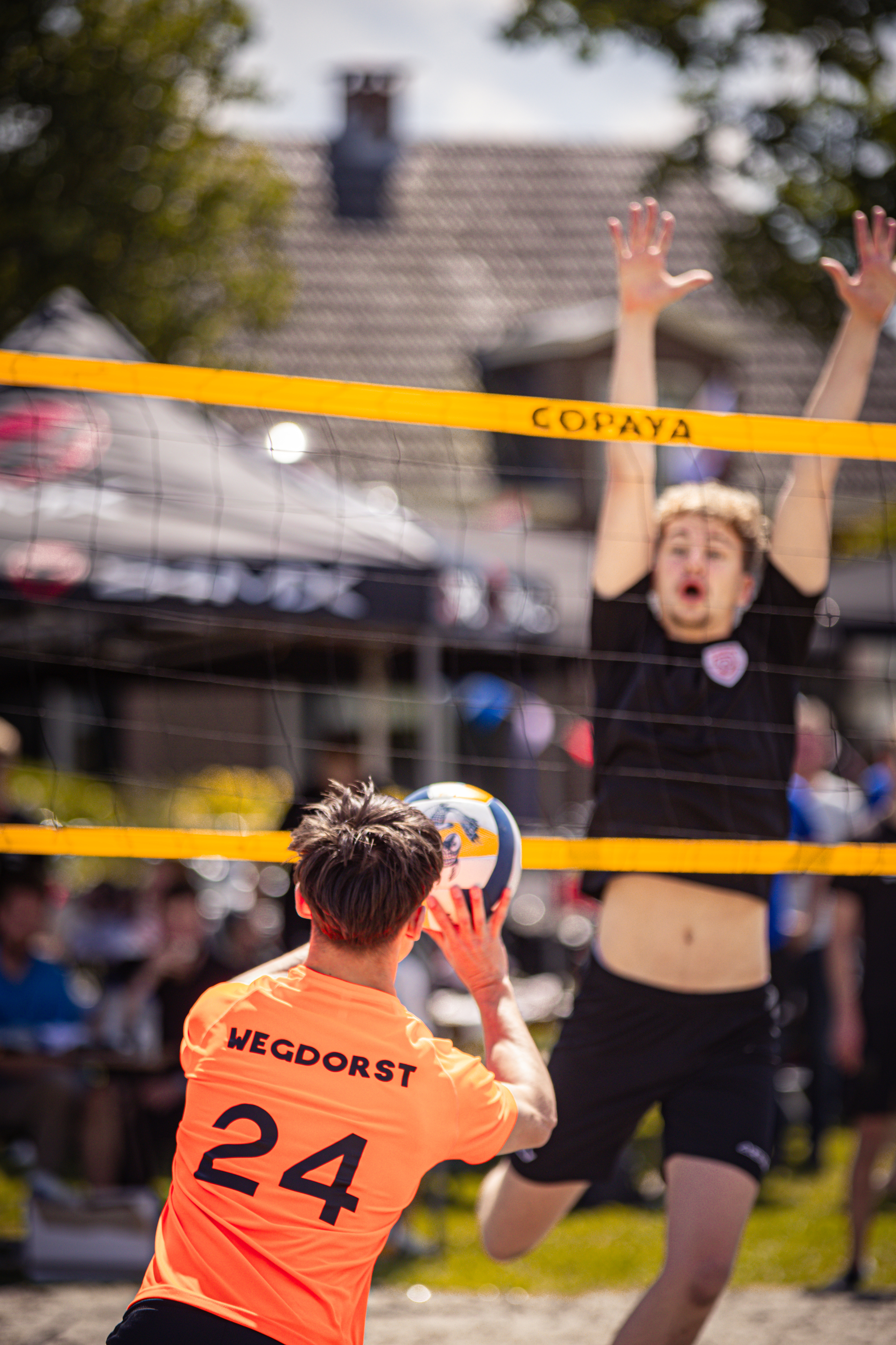 A volleyball player, number 24, is about to hit the ball as an opponent leaps above him.