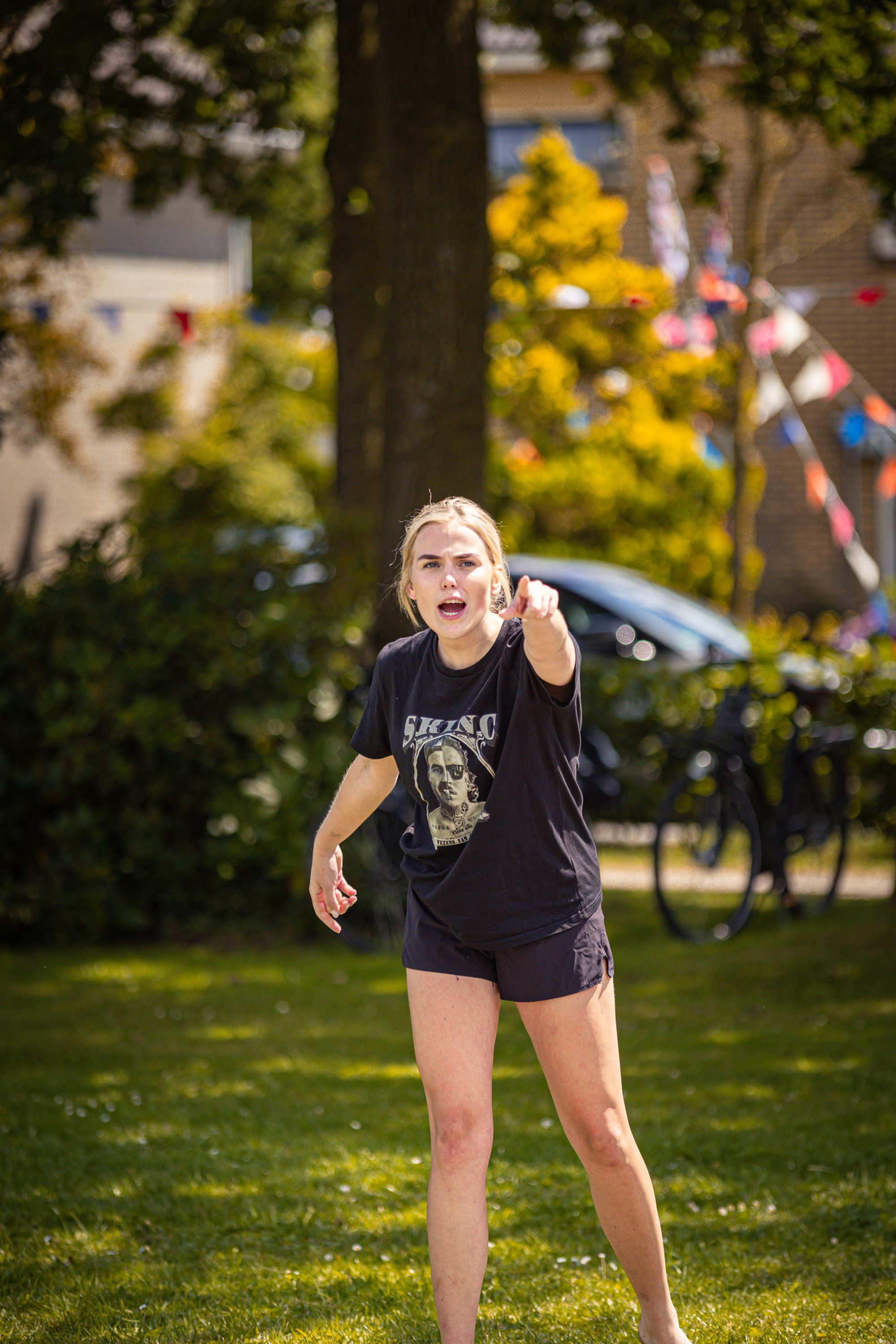 A woman pointing at something while wearing a black shirt that says "Beach Volleybal".