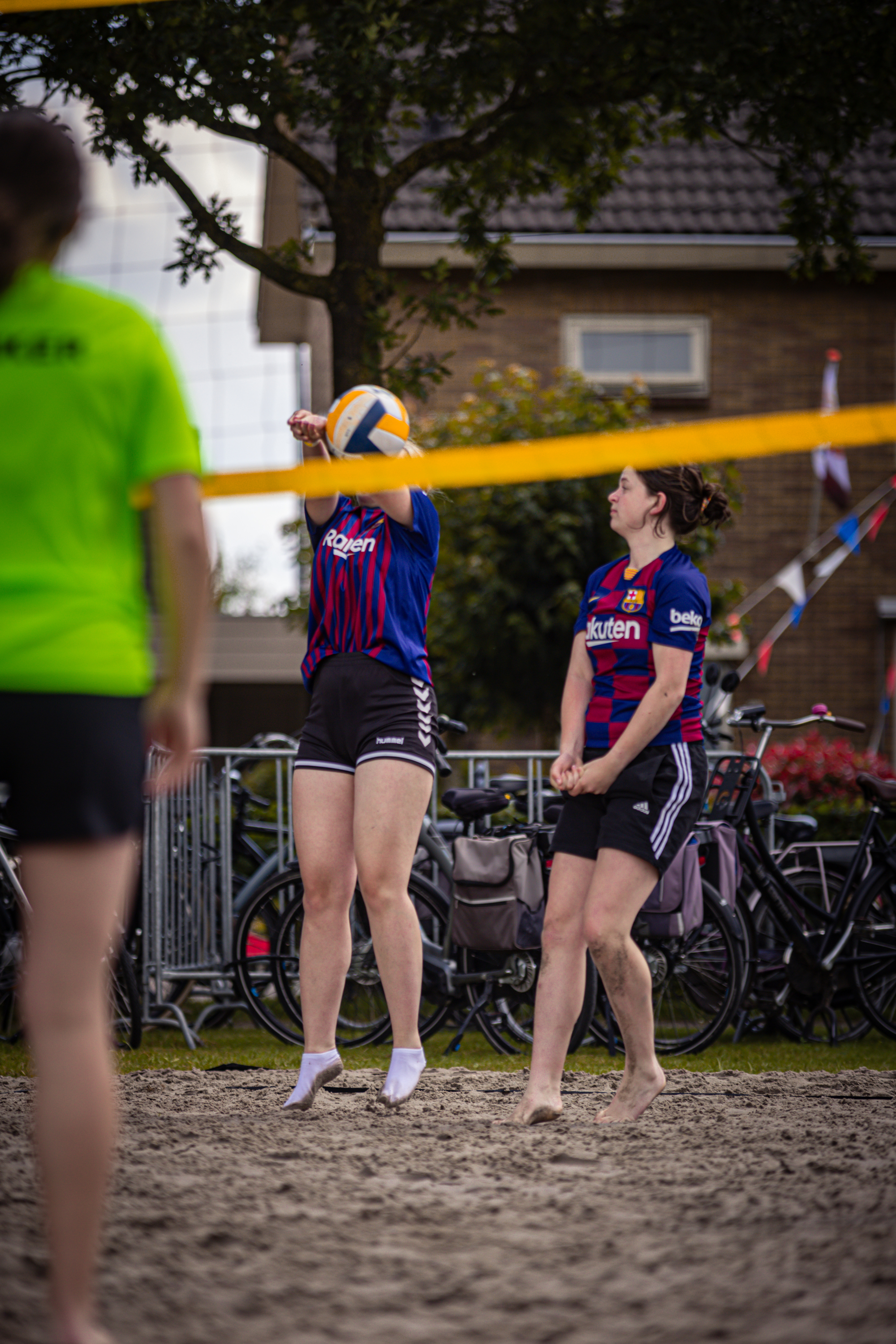 Two female athletes in blue and red striped outfits playing beach volleyball.