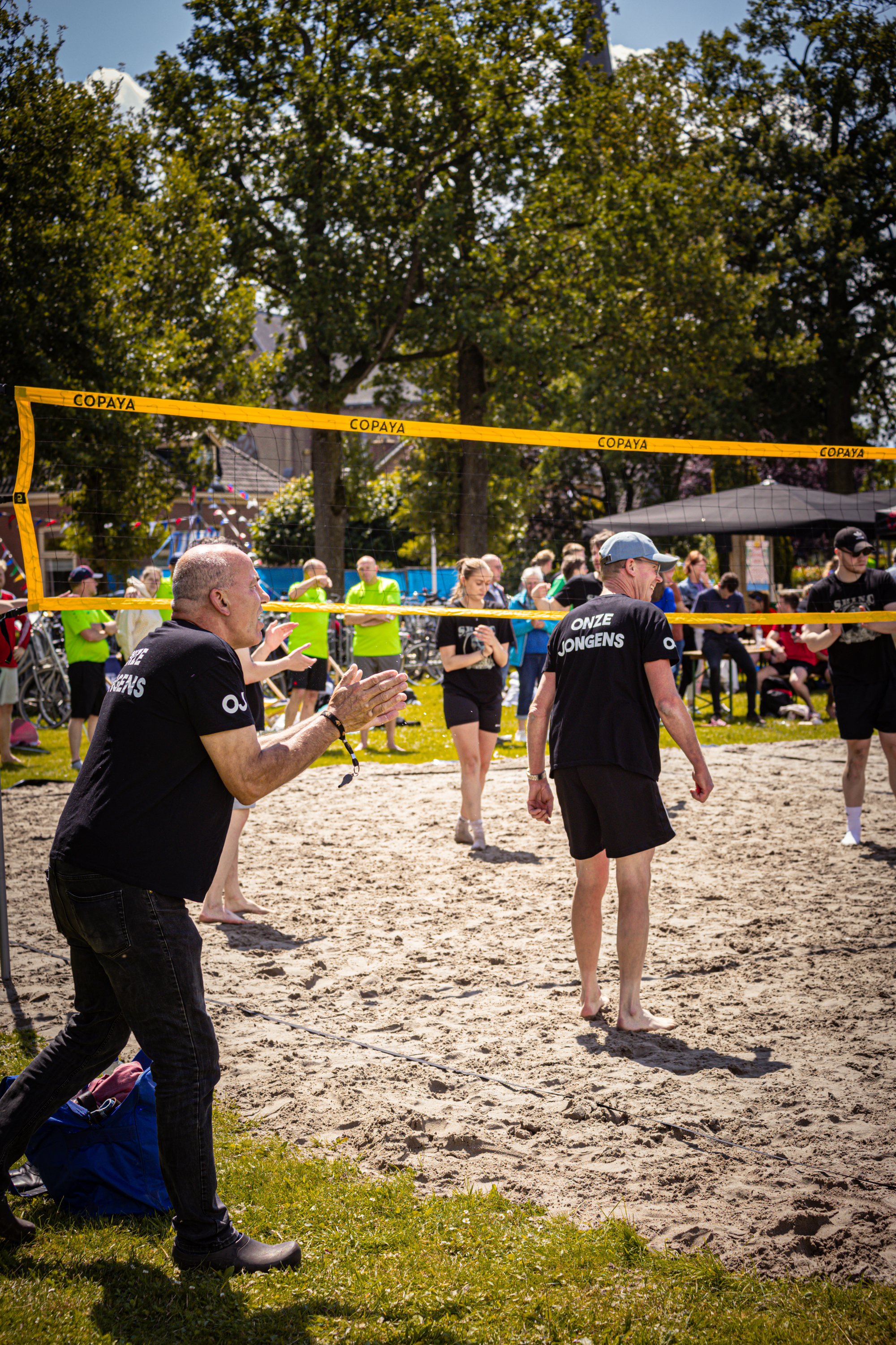 People playing beach volleyball and a man filming it.