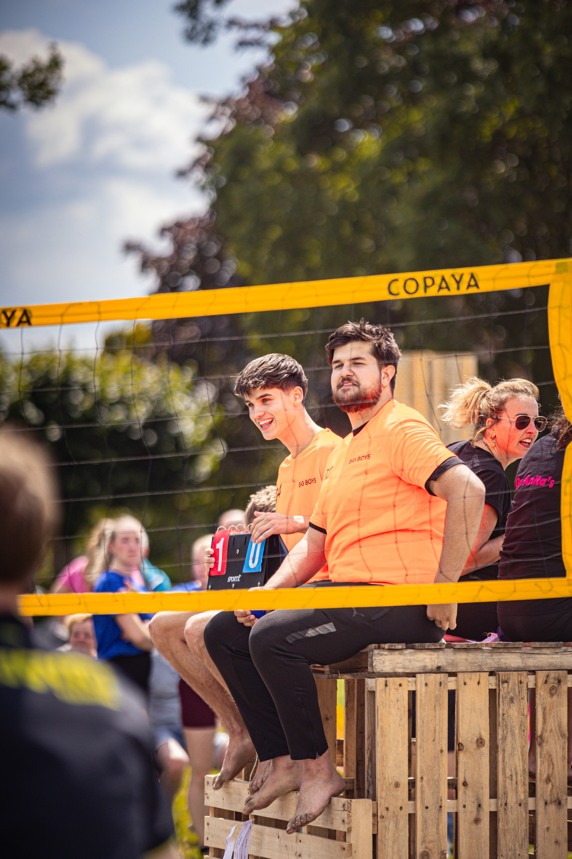 A group of people on a wooden pallet with an orange shirt saying Copaya.