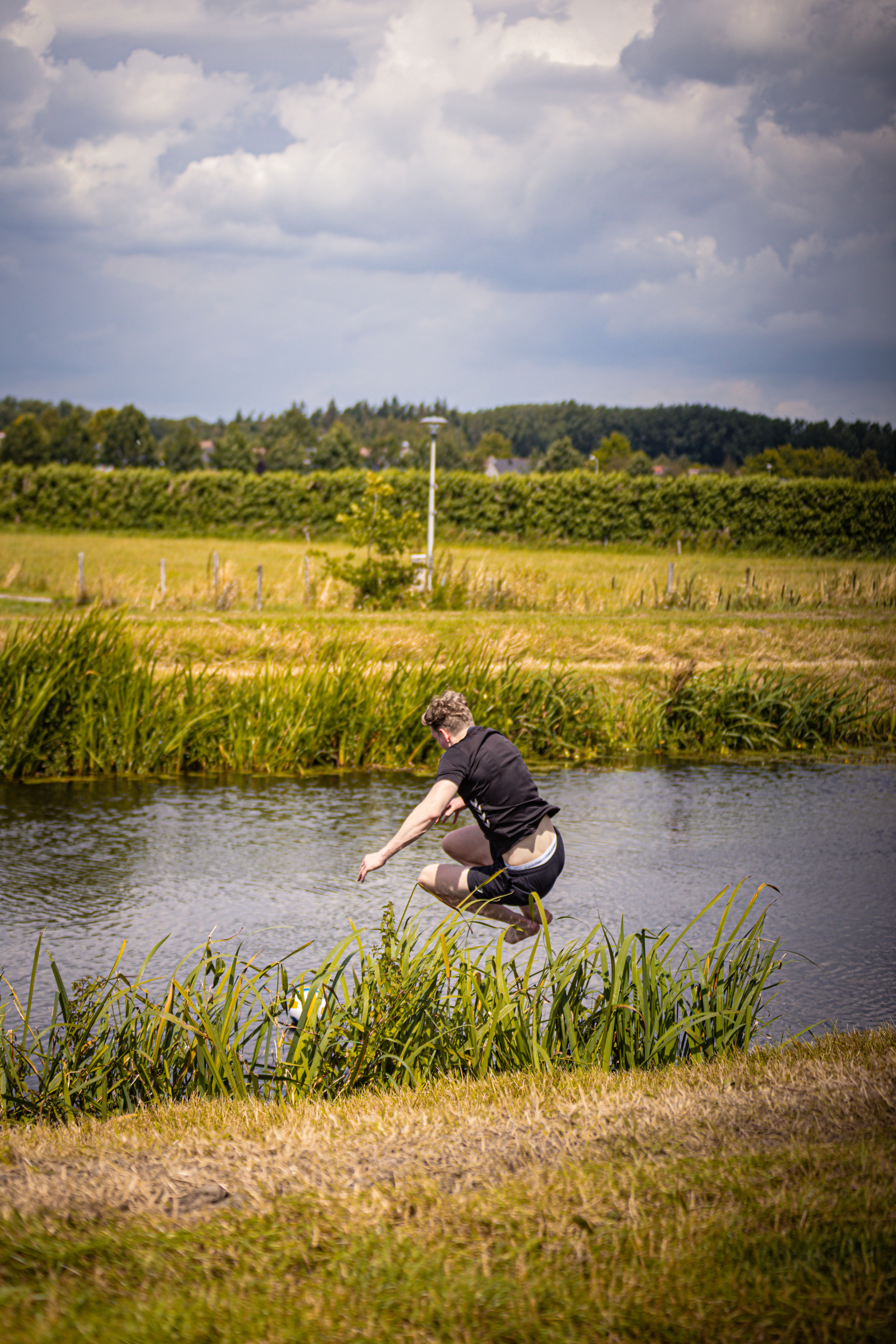 A man is diving into a river while wearing a wet suit.