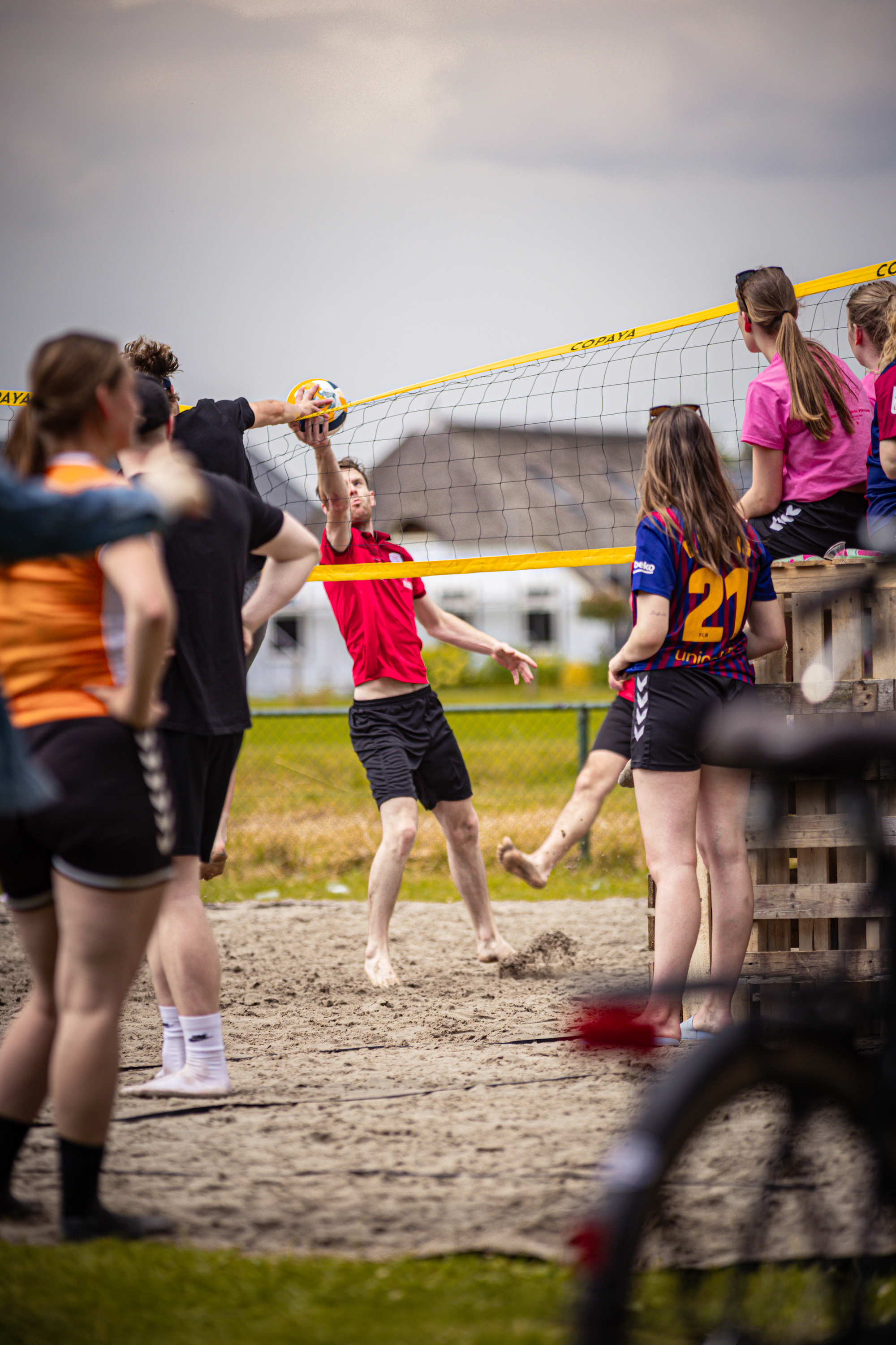 A group of people are playing beach volleyball on the shore.