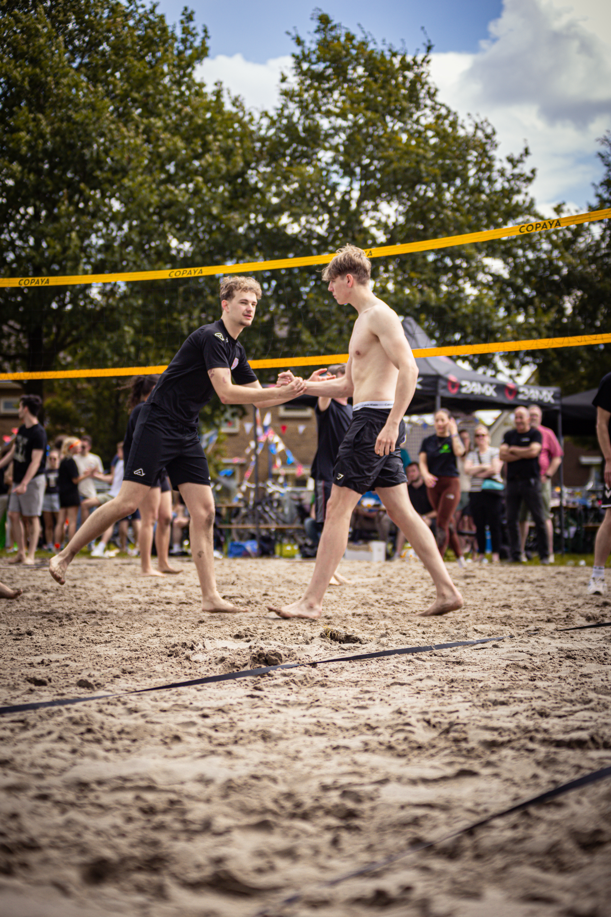 Two men play a game of beach volleyball on a sunny day.