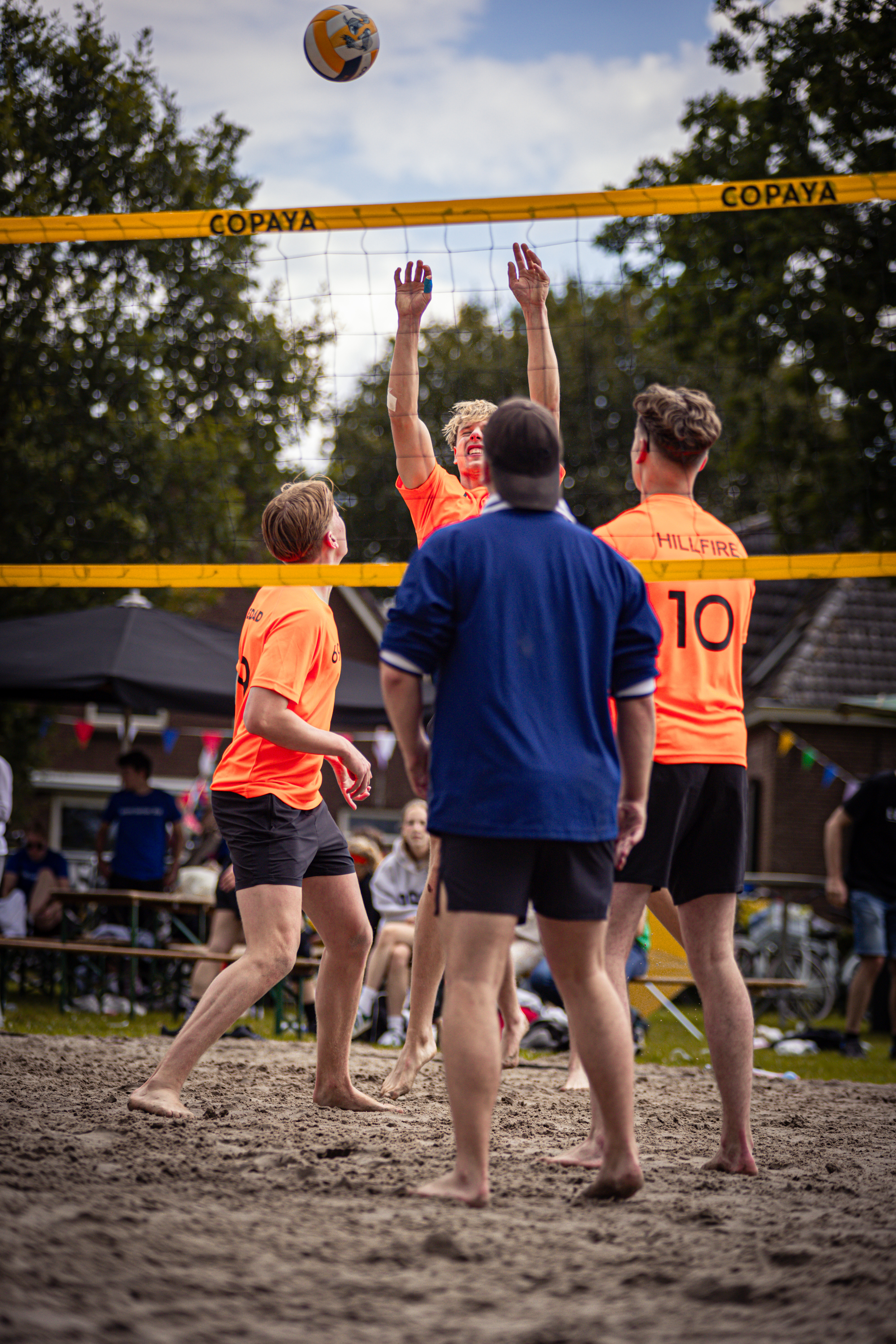 A group of young men playing volleyball on the beach.