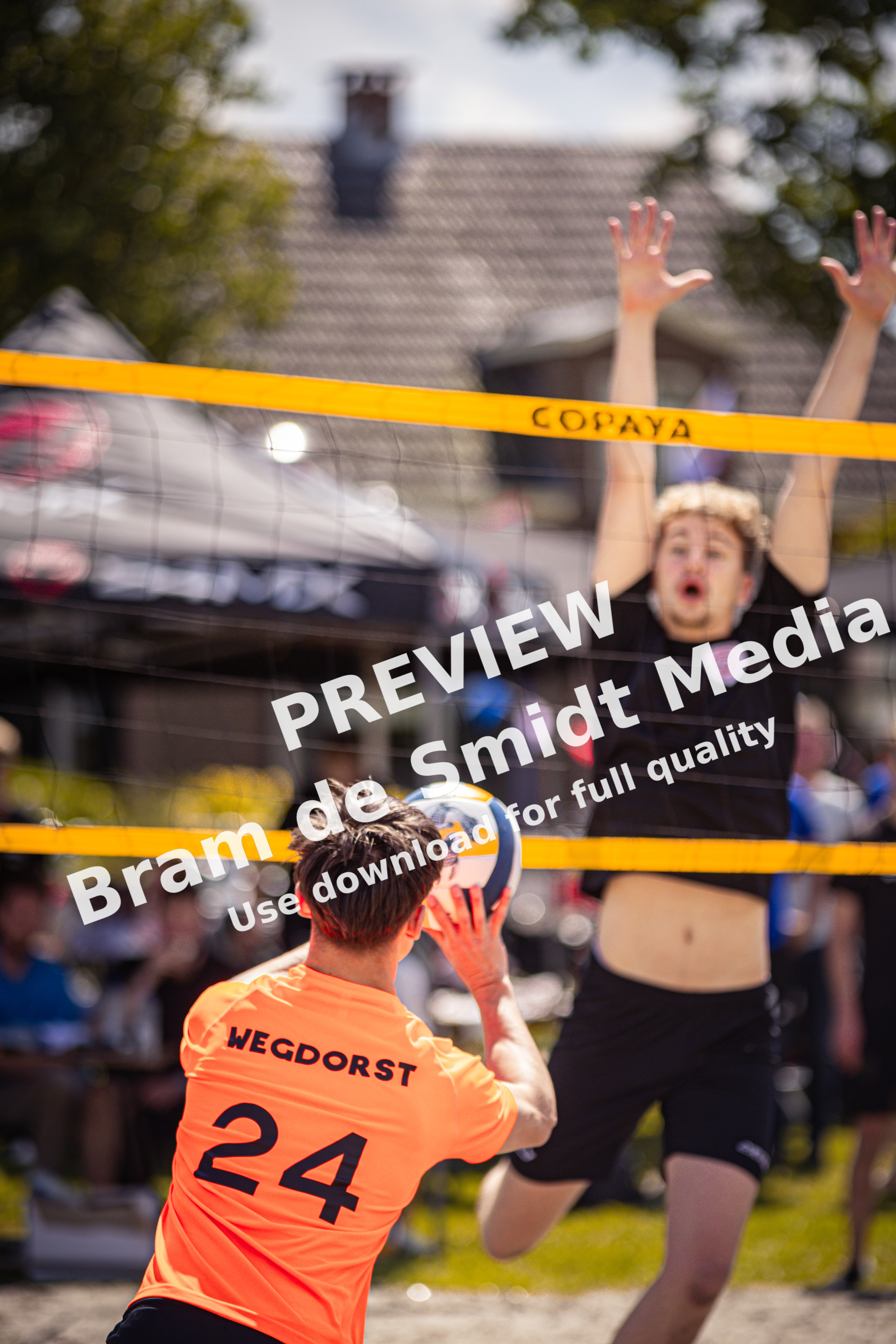 A volleyball player, number 24, is about to hit the ball as an opponent leaps above him.