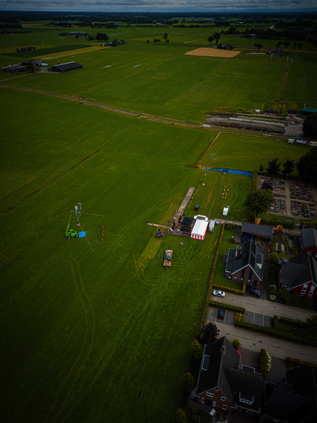 An aerial shot of a field with a large tent, cars and people in the distance. The event is called Kermis Boerhaar.