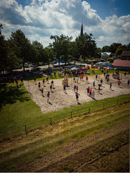 Several people are playing volleyball on a sandy field.