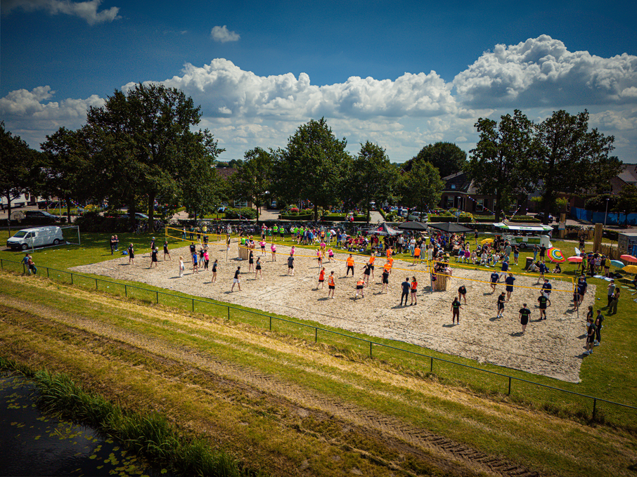 A group of people are playing volleyball on a sandy court.