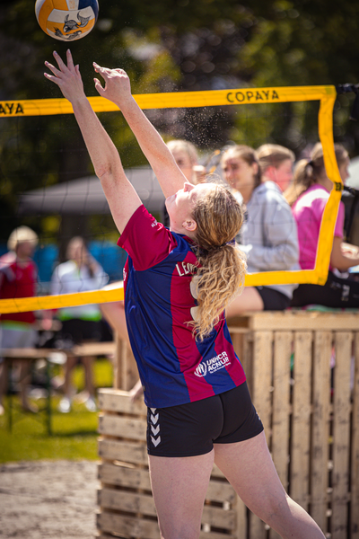 A girl playing volleyball wearing a blue and red jersey.