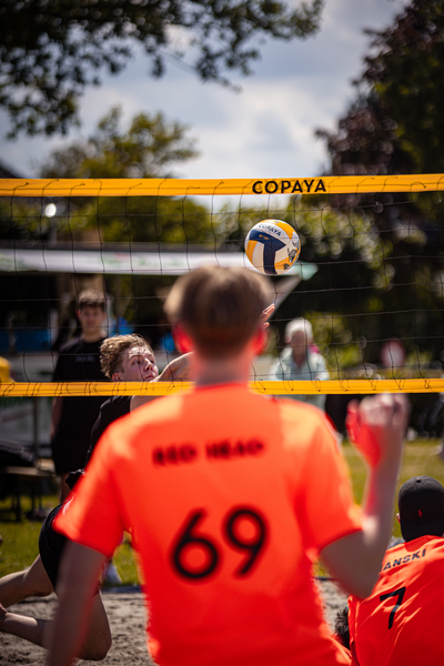 A man in a number 69 jersey is ready to receive a volley during a beach volleyball game.