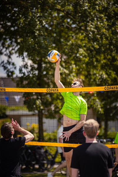 A man in a green shirt plays volleyball at a competition on Copaya beach.