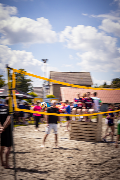 A group of people playing beach volleyball in front of a sign for Kermis Boerhaar.