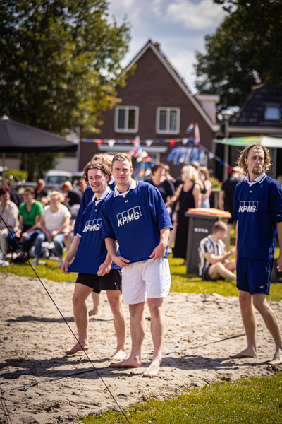 A group of people in beach volleyball uniforms are on a sandy court.