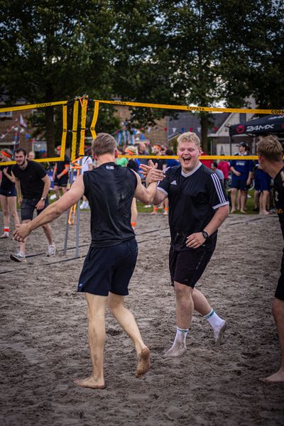 Two men are playing beach volleyball, one of whom has a shaved head.