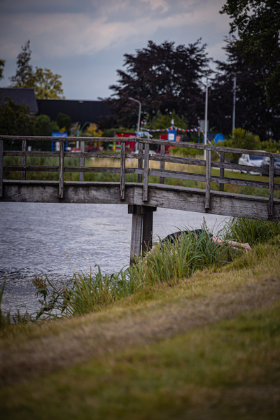 A person playing beach volleyball on a bridge overlooking water.