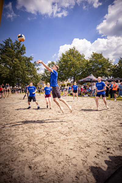 A group of people play volleyball on a sandy beach.