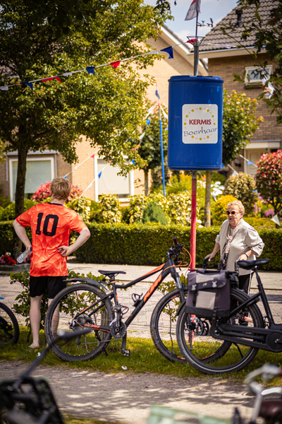 A woman is walking past a bike that says "Kermis Boerhaar" on it, and there's another person standing by the bike.