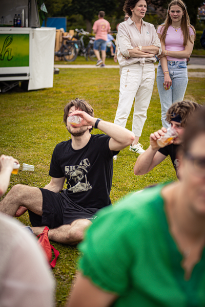 Four people in a field, two of them drinking and talking.