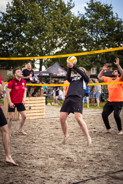 A group of men are playing beach volleyball on a sunny day.