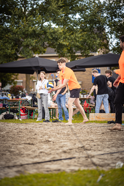 A group of people playing volleyball at a beach event.