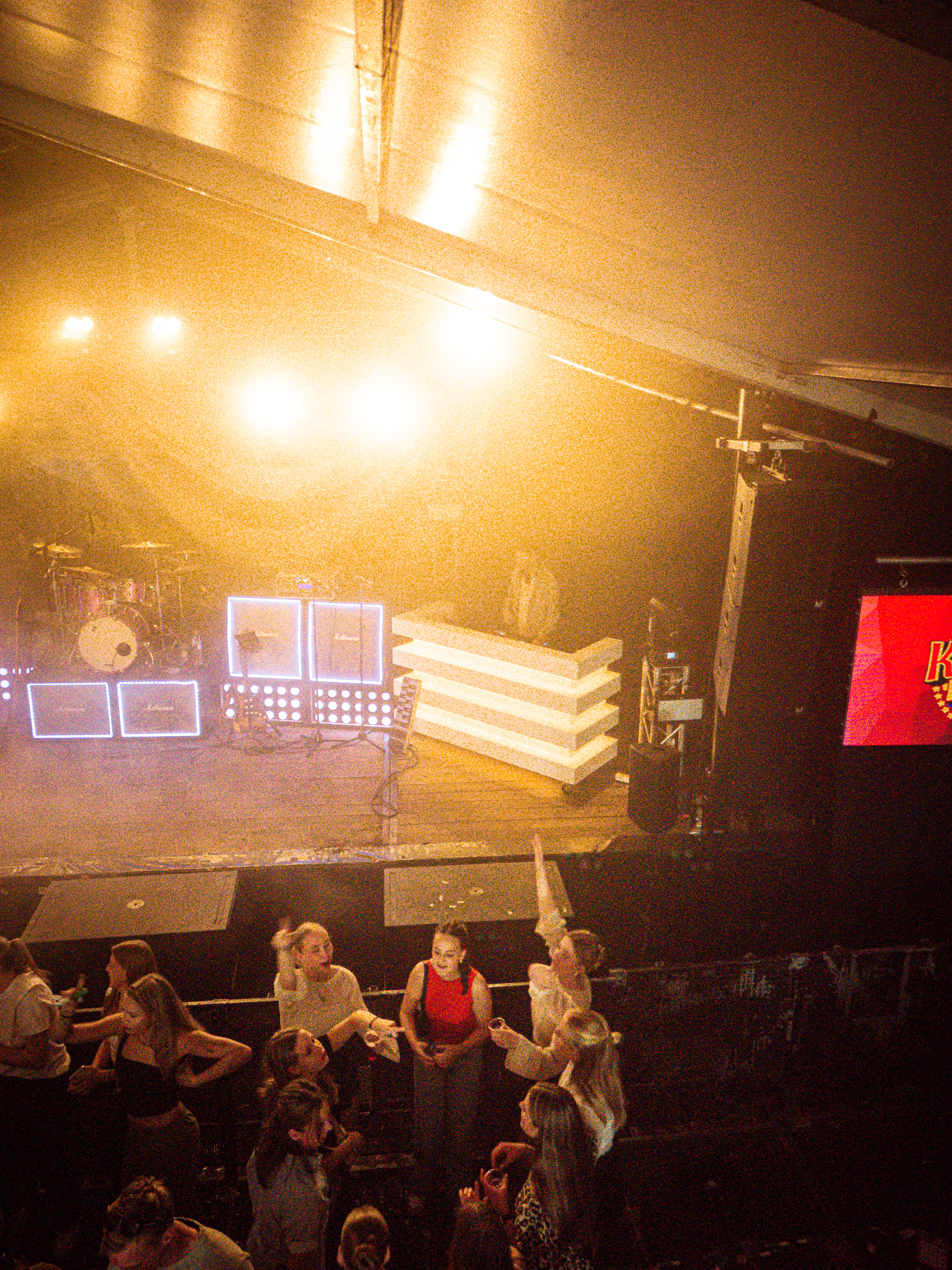 People at an indoor concert are watching a band perform on stage.